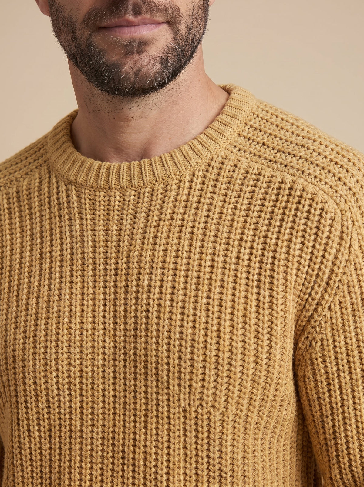 Detalle del punto grueso y del cuello redondo del jersey mostaza